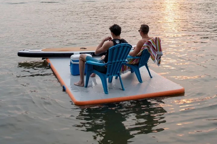 a group of people sitting on a bench next to a lake